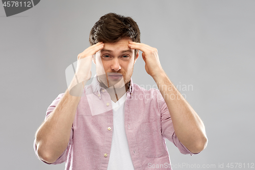 Image of unhappy young man suffering from headache
