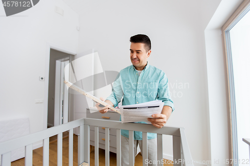 Image of father with manual assembling baby bed at home