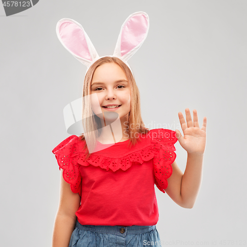 Image of happy girl wearing easter bunny ears waving hand