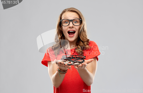 Image of surprised teenage girl holding pile of glasses