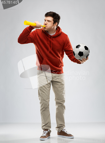 Image of football fan with soccer ball blowing horn