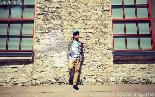 Image of man with smartphone drinking coffee on city street