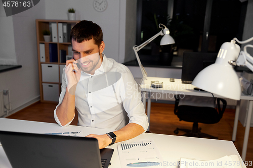 Image of businessman calling on smartphone at night office