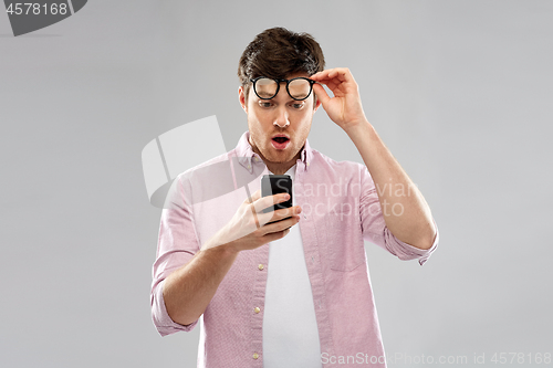 Image of embarrassed young man looking at smartphone