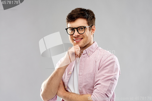 Image of smiling young man in glasses over grey background