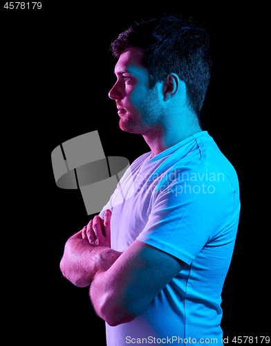 Image of man with crossed arms over neon lights in darkness