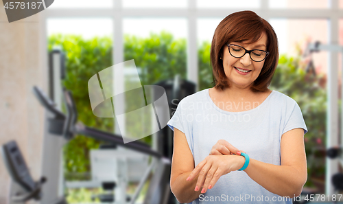 Image of smiling senior woman with fitness tracker in gym