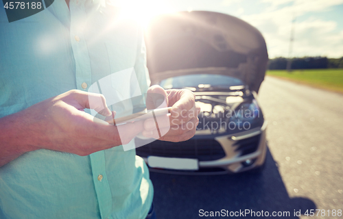 Image of close up of man with smartphone and broken car