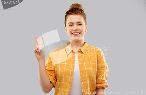 Image of smiling red haired teenage girl showing peace