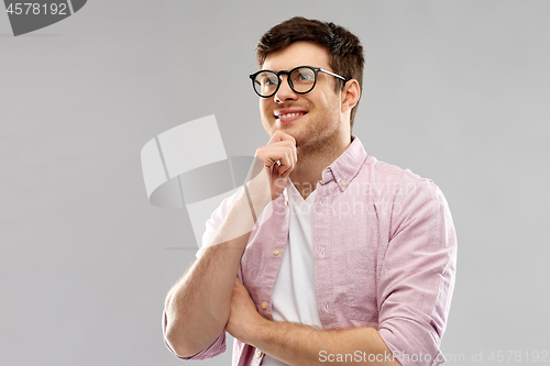 Image of smiling young man in glasses over grey background