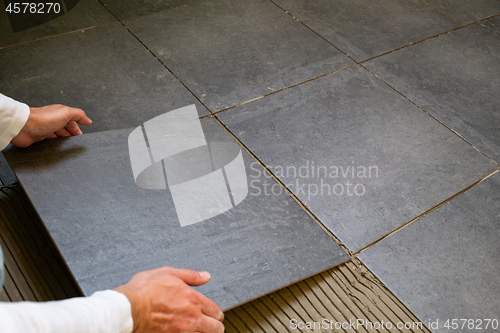 Image of Tiler installing ceramic tiles on a floor