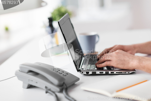Image of hands typing on laptop and desk set on table