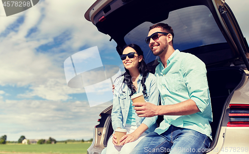 Image of happy couple with coffee at hatchback car trunk