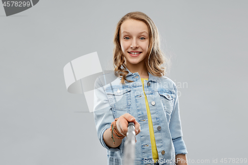 Image of teenage girl taking picture by selfie stick