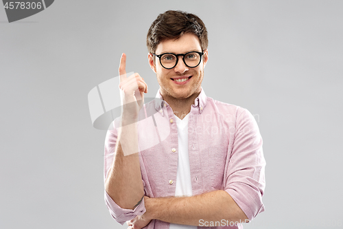 Image of smiling young man in glasses pointing finger up