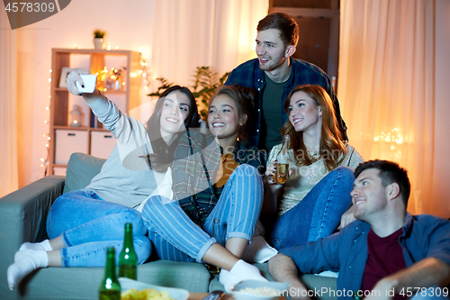 Image of happy friends taking selfie by smartphone at home