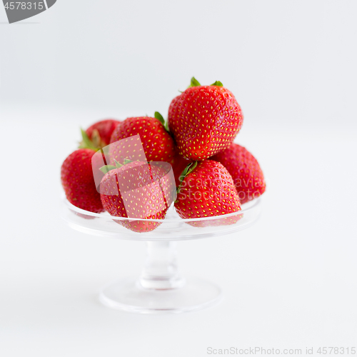 Image of strawberries on glass stand over white background