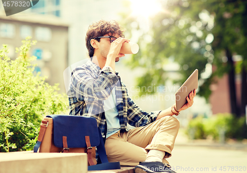 Image of man with tablet pc and coffee on city street bench