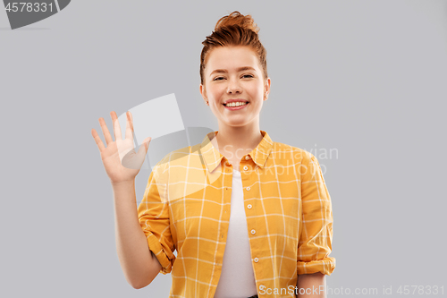 Image of smiling red haired teenage girl waving hand