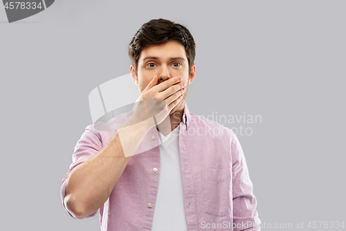 Image of shocked young man covering his mouth by hand