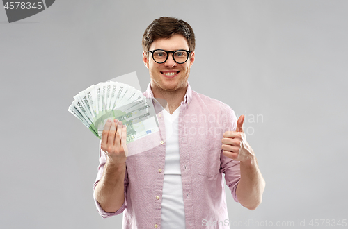 Image of happy young man with euro money showing thumbs up