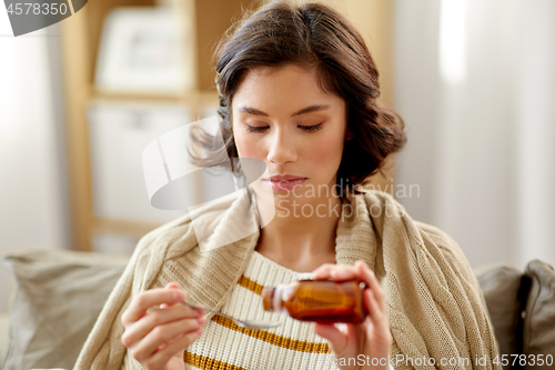 Image of sick woman with antipyretic or cough syrup at home