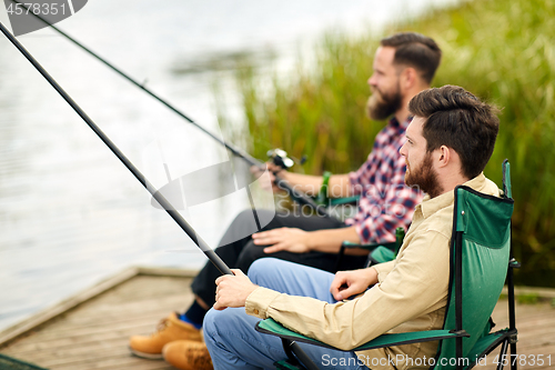 Image of friends with fishing rods at lake or river