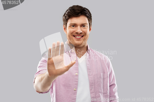 Image of smiling young man showing his palm