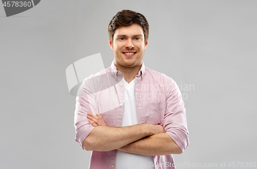 Image of smiling young man with crossed hands over grey