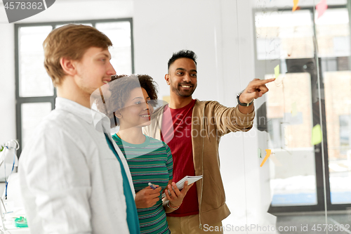 Image of happy creative team looking at office glass board