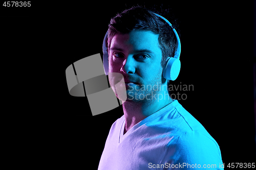 Image of man in headphones over neon lights of night club