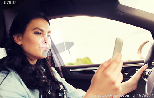 Image of happy woman driving car with smarhphone