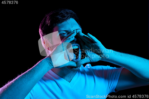 Image of angry man screaming over neon lights in dark room