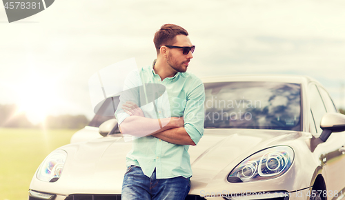 Image of happy man standing at car outdoors