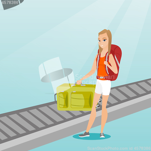 Image of Woman picking up suitcase from conveyor belt.