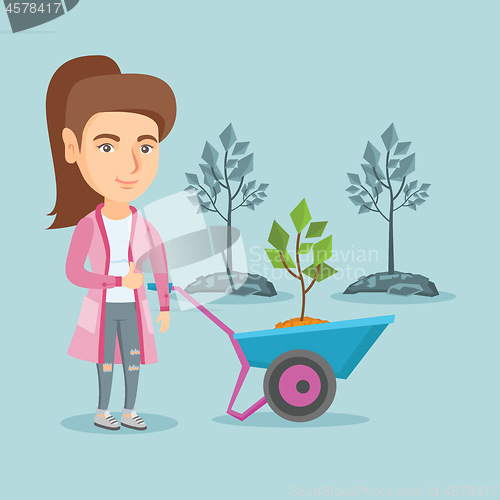 Image of Caucasian woman pushing wheelbarrow with plant.