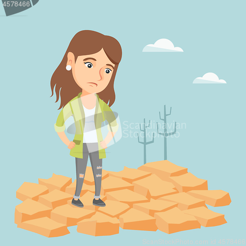 Image of Sad woman standing on cracked earth in the desert.