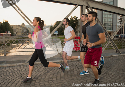 Image of group of young people jogging across the bridge