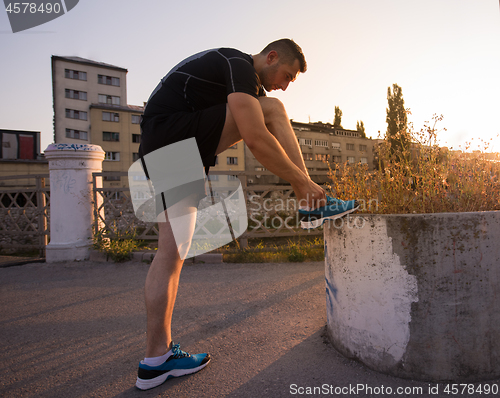 Image of man tying running shoes laces