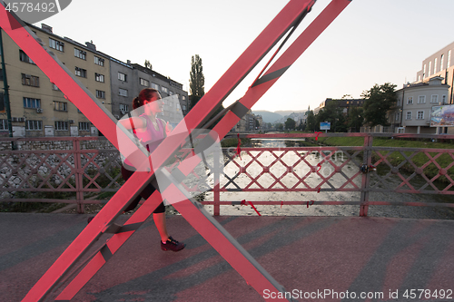 Image of woman jogging across the bridge at sunny morning