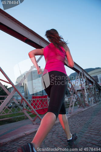 Image of woman jogging across the bridge at sunny morning