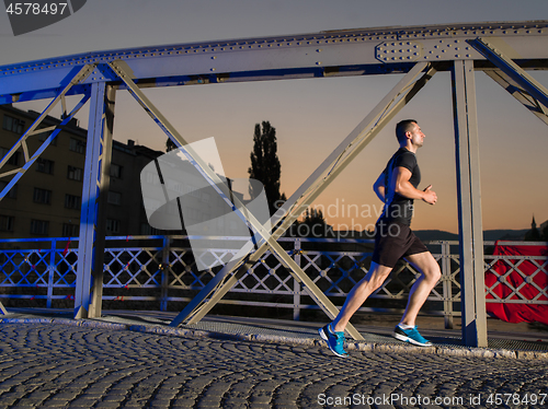 Image of man jogging across the bridge in the city