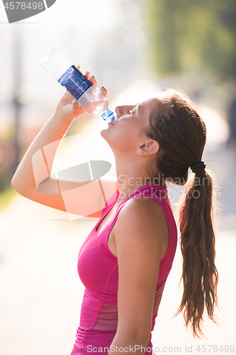 Image of woman drinking water from a bottle after jogging