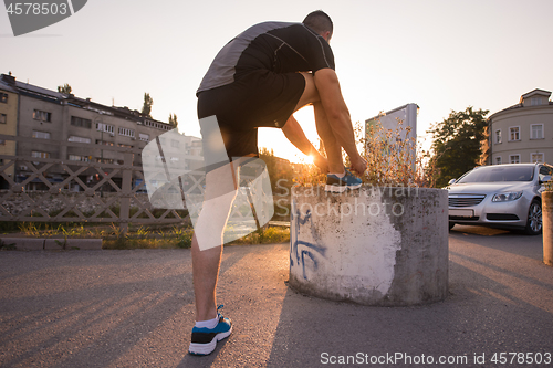 Image of man tying running shoes laces