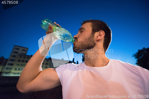 Image of man drinking water after running session