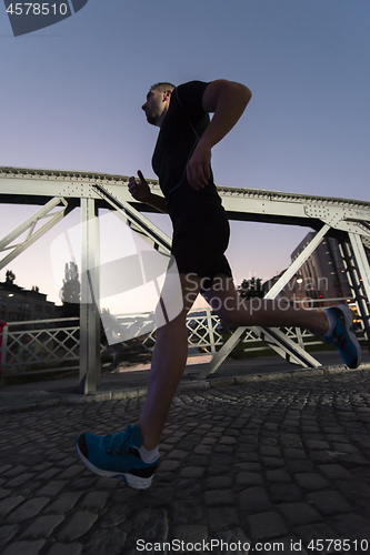 Image of man jogging across the bridge in the city