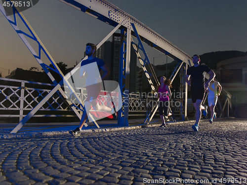 Image of young people jogging across the bridge