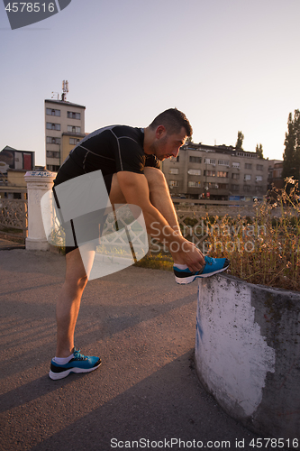 Image of man tying running shoes laces