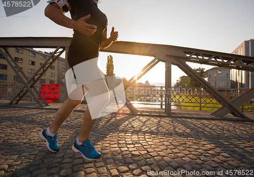 Image of man jogging across the bridge at sunny morning