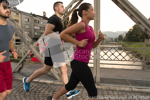 Image of group of young people jogging across the bridge